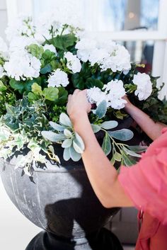 a woman is arranging flowers in a large pot