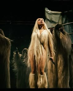 a woman with long blonde hair standing in front of many furry animals