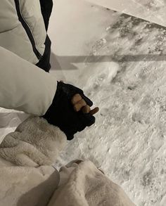 a person standing in the snow holding onto their gloves