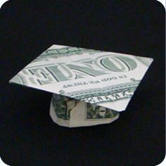 an origami graduation cap made out of one hundred dollar bills on black background