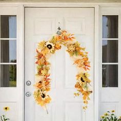 a white front door with an orange and yellow flower wreath on it's side