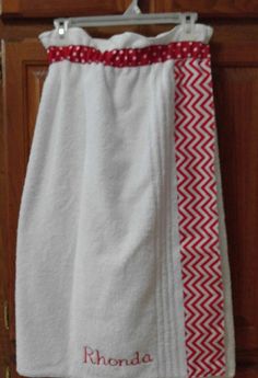 a white towel with red trim hanging from a hook on a wooden cabinet door next to a pair of scissors