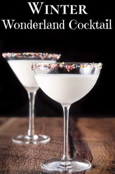 two glasses filled with white liquid and sprinkles on top of a wooden table