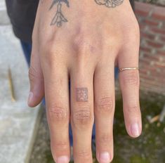 a person with tattoos on their fingers and hand