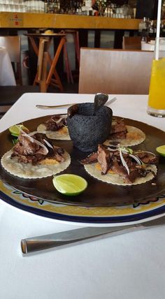 a plate that has food on it and some limes next to the plate is sitting on a table