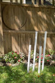 three metal poles sticking out of the ground in front of a wooden fence and flowers