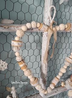 a heart shaped decoration made out of wood beads and other items hanging from a chicken wire fence