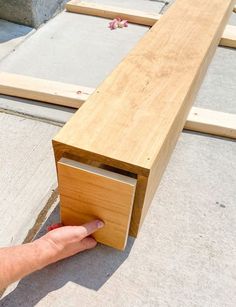 a hand reaching for a piece of wood on top of a bench that is being built