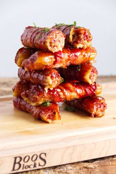 a stack of bacon wrapped in ketchup on top of a wooden cutting board