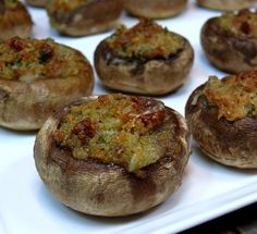 several stuffed mushrooms are sitting on a white platter and ready to be cooked in the oven