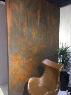 a chair sitting in front of a wall with a painting on it's side