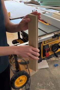 a person holding a piece of wood in front of a table sawdusting machine