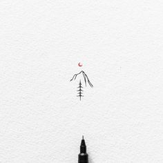 an ink pen is sitting on top of a piece of paper with a mountain in the background