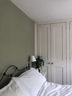 a bed with white linens and a plant on the headboard next to it