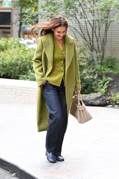 a woman is walking down the street with her hand in her pocket and holding a purse