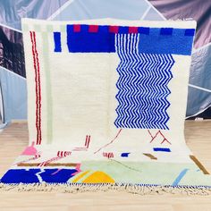 two rugs on the floor in front of a blue and white wall with an abstract design