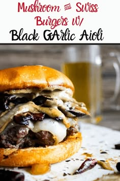 mushroom and swiss burgers with black garlic aioli on a white plate next to a glass of beer