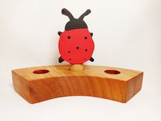 a ladybug toy sitting on top of a wooden block with holes in it