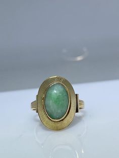 14K yellow gold ring with a natural jade. This vintage piece from the 70’s is delicately made from the top of its scrolled shank to the textured bezel holding the stone in. The oblong oval Jade cabochon is a lovely green hue with white undertones. The basket is nice and opened eliminating any unnecessary weight. It measures 17mm x 12mm across the top and makes for the perfect statement ring. Finger size is 6.5 Feel free to message me if you have any other questions. Oval Jade Rings In Yellow Gold, Vintage Polished Emerald Ring With Oval Cabochon, Vintage Emerald Oval Cabochon Ring With Polished Finish, Vintage 14k Gold Oval Cabochon Emerald Ring, Vintage 14k Gold Emerald Oval Cabochon Ring, Vintage Oval Cabochon Emerald Ring With Polished Finish, Antique Oval Emerald Ring Stamped 14k, Vintage Oval Emerald Ring In 14k Gold, Vintage Oval Gemstone Signet Ring