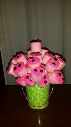 a green bucket filled with pink donuts on top of a table