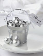 a metal bucket filled with silver balls on top of a white plate