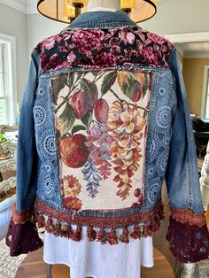 the back of a jacket with flowers and leaves on it, sitting on a table