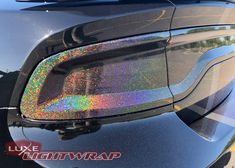 the rear end of a black car with holographics on it's hood