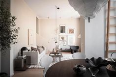 a living room filled with furniture next to a wooden table and ladder in front of a white wall