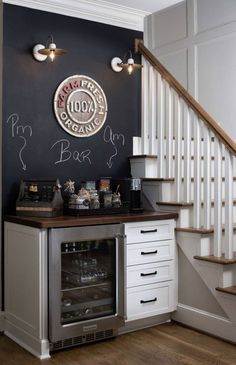 a kitchen with a wine cooler under the stairs and a clock on the wall above it