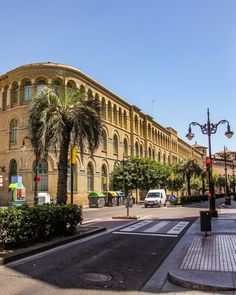 an old building with palm trees in front of it on the corner of a street