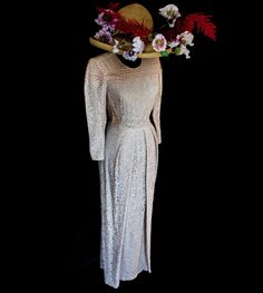 a white dress and hat with flowers on the top, against a black background that is lit up