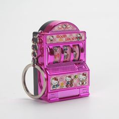 a pink coin machine keychain with hello kitty pictures on the front and sides