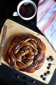 a pastry on a cutting board next to a cup of coffee