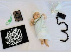 a baby laying on top of a white blanket next to some beads and other items