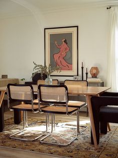 a dining room table with four chairs and a painting hanging on the wall behind it