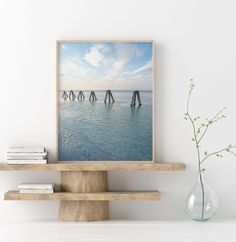 an art print on a shelf next to a vase with flowers