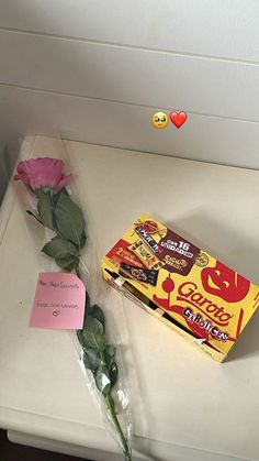 a pink rose and candy bar wrapped in cellophane next to a valentine's day card