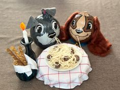 three stuffed animals sitting next to a plate of spaghetti