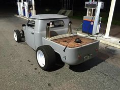 an old pickup truck with a gas pump attached to it's back end is parked in front of a gas station