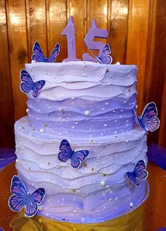 a purple cake with butterflies on it and the number one is decorated in white frosting