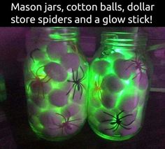 two mason jars with spider webs on them are glowing green and purple in the dark