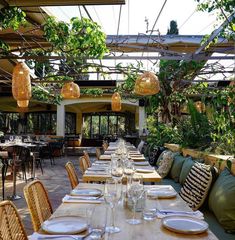 an outdoor dining area with tables, chairs and hanging lights in the middle of it