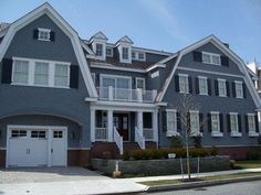 a large gray house with white trim on the front and side windows, along with two garages