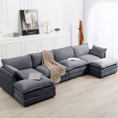 a living room with white walls and wood flooring has a gray sectional sofa set