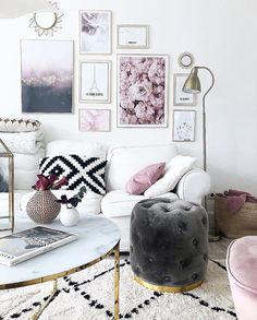 a living room filled with white furniture and pictures on the wall above it's coffee table