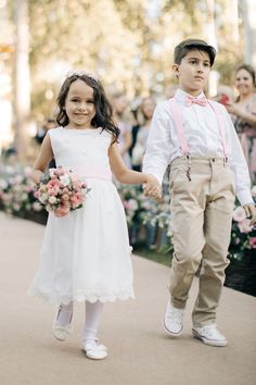 a young boy and girl are walking down the street together, holding hands with each other