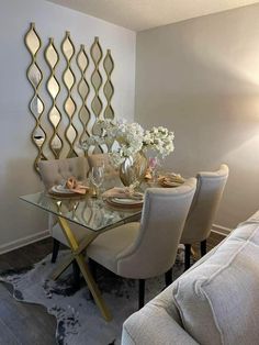 a dining room table with chairs and a glass top centerpiece on the wall in front of it