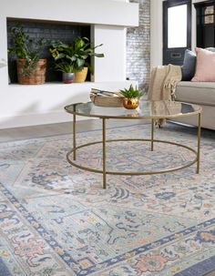 a living room with a couch, coffee table and rug in front of a fireplace