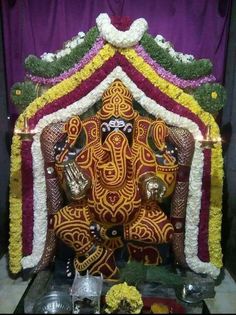 an elephant statue is decorated with flowers and other decorations in front of a purple curtain