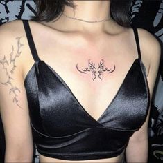 a woman with a tattoo on her chest wearing a black bra and silver choker